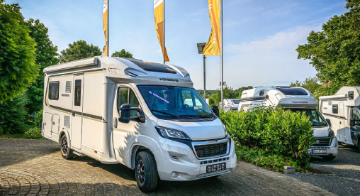 Vermietung - Familie sitzt vorm Wohnmobil