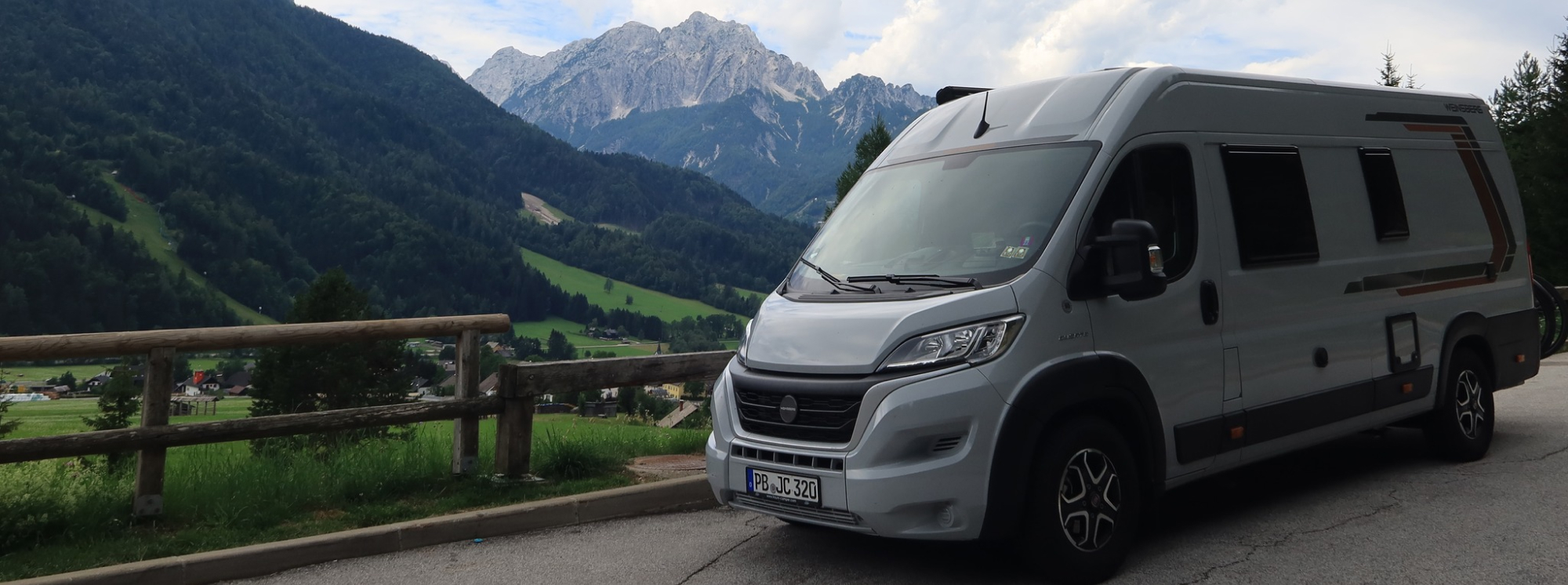 Wohnmobil auf Landstraße mit Bergen im Hintergrund