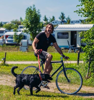 Mann fährt auf einem Fahrrad mit einem Hund an der Leine