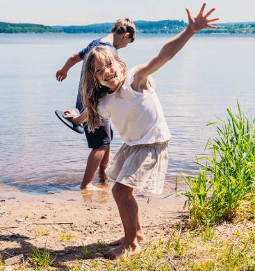 Mädchen und Junge lachend vorm See